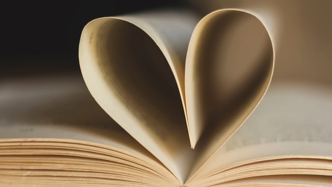 Ein Buch, das in der Mitte aufgeschlagen ist. Die Buchseiten sind zu einem Herz geformt.