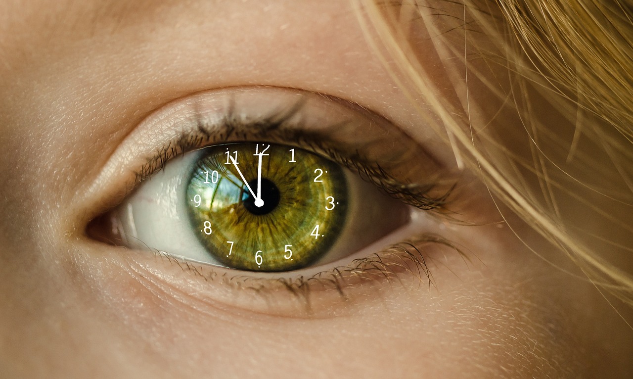 Auge eines Kindes, in dem eine Uhr abgebildet ist, die auf 5 vor 12 steht.